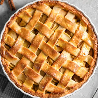An overhead shot of a baked fruit pie featuring a golden-brown, woven lattice crust in a white, fluted pie dish