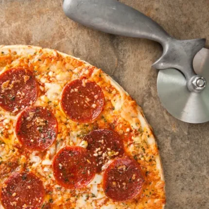 Baked frozen pizza next to a pizza cutter