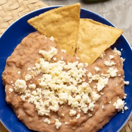 Refried beans with sprinkled cheese and chips closeup