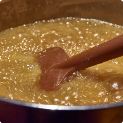 Butterscotch cooking process with a spoon stirring in a pot
