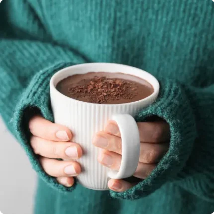 Person holding hot cocoa in a mug, closeup of hands