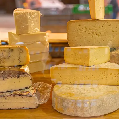 A stacked display of large yellow cheese wheels and blocks