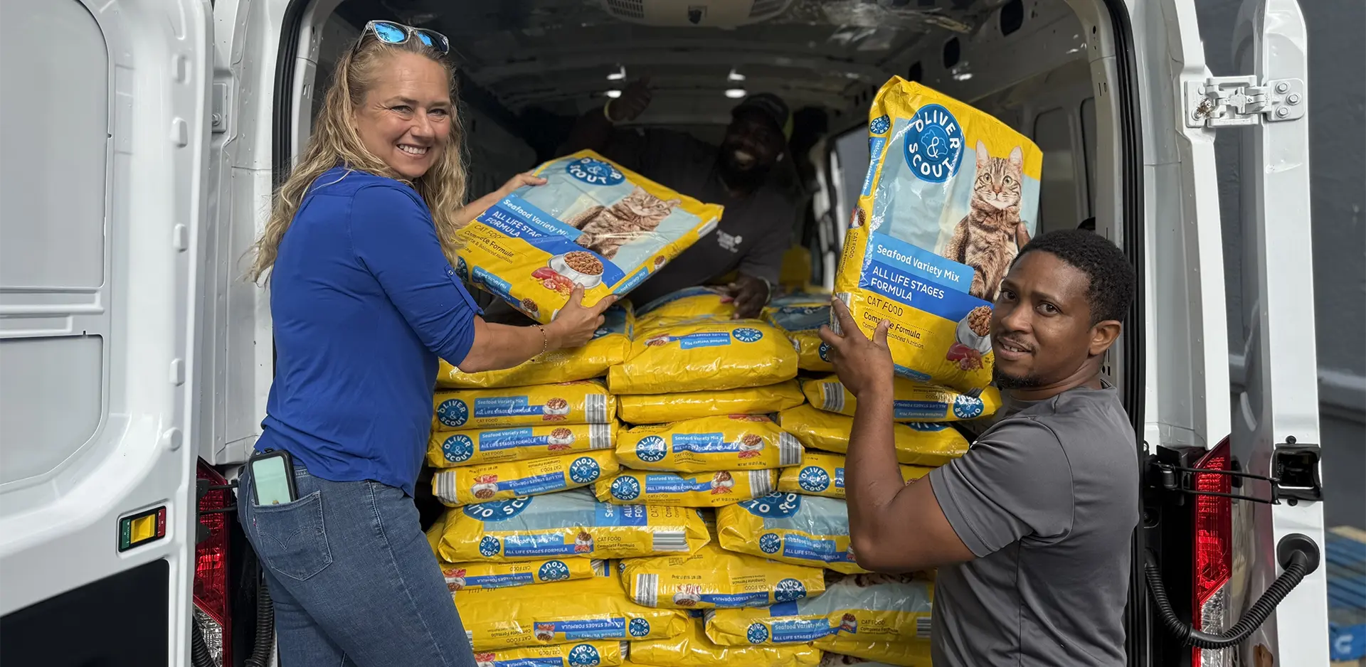 Save A Lot employees unloading a van with Oliver & Scout brand cat food