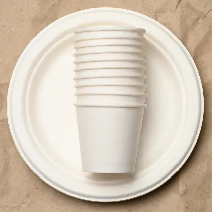 A top-down view of a stack of white paper cups resting in the center of white paper plates