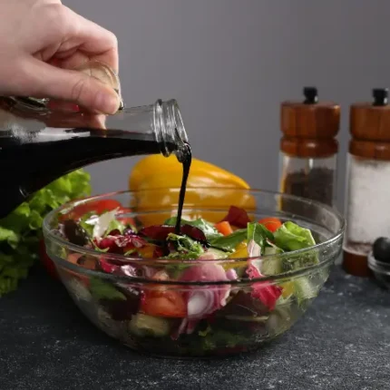 Vinegar dressing being poured onto a salad