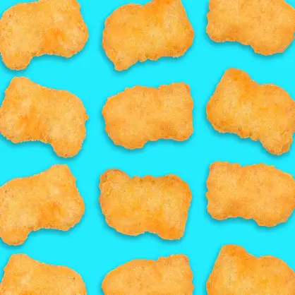 A grid pattern of several identical, golden-brown chicken nuggets arranged neatly against a bright, solid blue background
